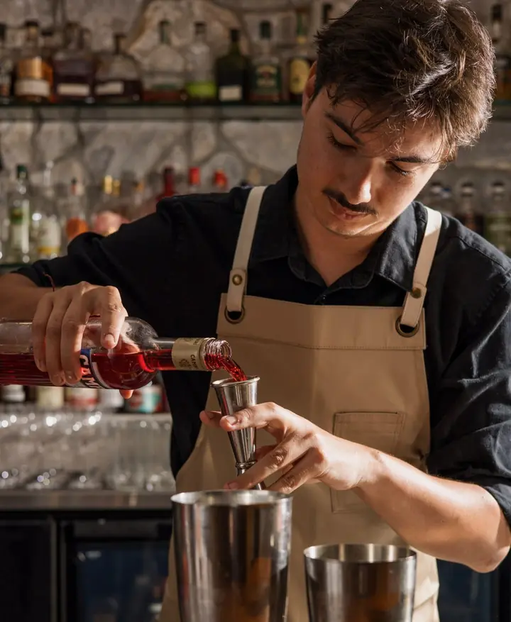 Timothée dose un apéritif au jigger derrière le bar